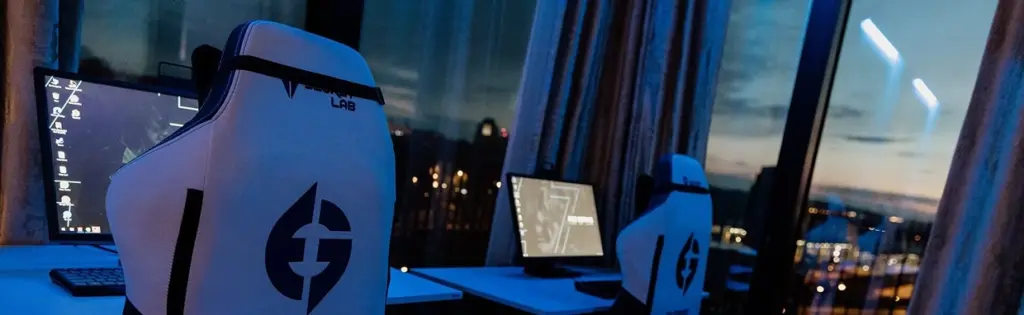 moderne esports-trainingsruimte met gamingstoelen, computerschermen en bureaus bij een groot raam, professionele gameomgeving voorbereid voor competitief gamen tijdens de avonduren